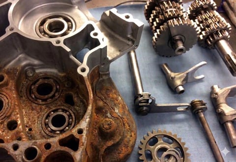 Disassembled engine parts including cylinder head, gears, and metal components laid out for maintenance or repair.