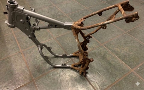 Rusty metal bicycle frame and fork components on tiled floor