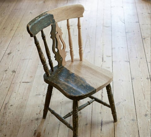 Rustic wooden chair with weathered finish and spindle back sitting on light wood flooring