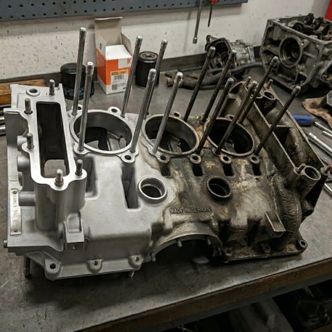 Disassembled engine block with multiple pistons and rods on a workbench in an auto repair shop