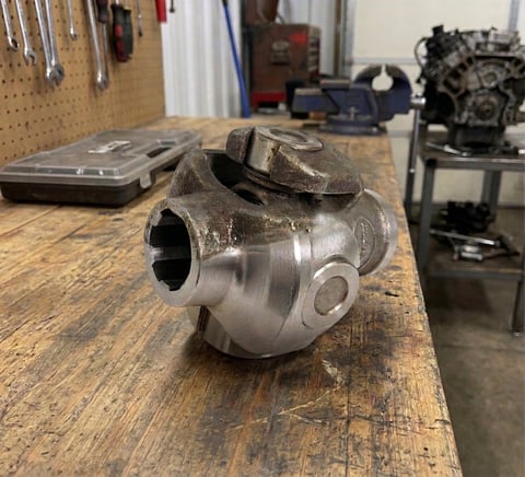 Close-up of a metal automotive turbocharger component on a workbench in a garage workshop