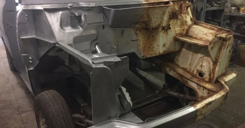 Disassembled vehicle door and rusted metal parts displayed in workshop