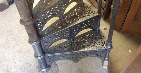 Ornate cast iron fireplace insert with decorative scrollwork panels and cylindrical side posts